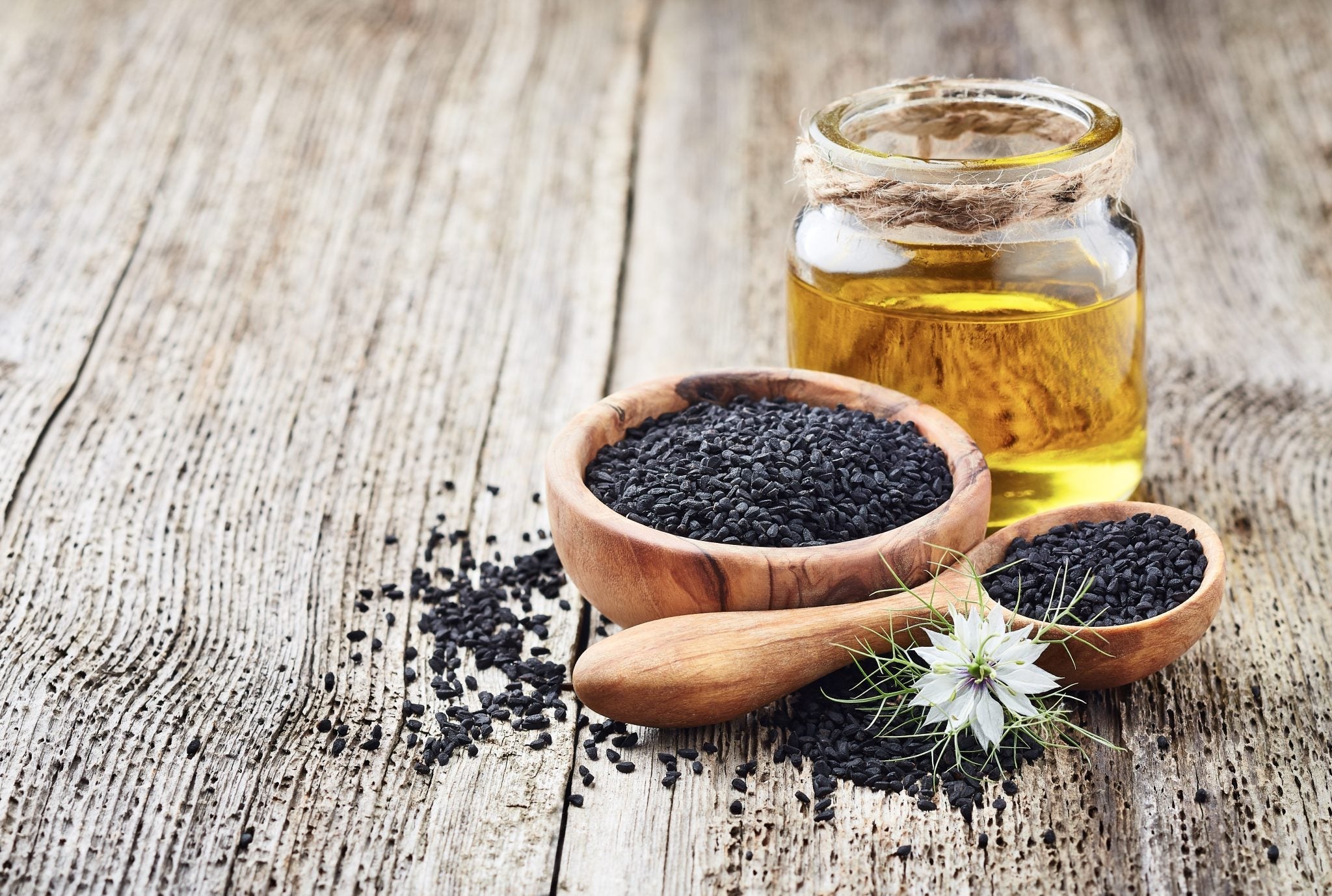olej z czarnuszki – zastosowanie, butelka oleju i nasiona Nigella sativa